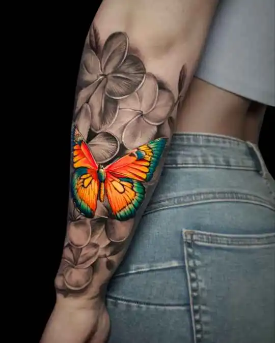 Farbenfrohes Schmetterling-Tattoo mit Blumenmotiv auf dem Unterarm, Köln | Colorful butterfly tattoo with flower motif on the forearm, Cologne
