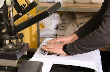 Young man printing on t-shirt at worksho