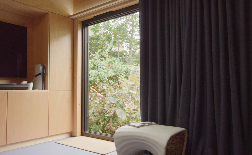 Interior view from London garden room with armchair by large window overlooking garden