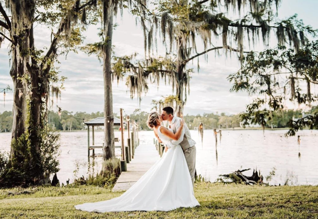 Wedding venue in Spartanburg, Wedding venue in Greenville, Wedding venue in the upstate of SC, all inclusive wedding venue, barn wedding venue, luxury barn venue, outdoor wedding in Spartanburg, Wedding venue near me, bride and groom kissing with lake background