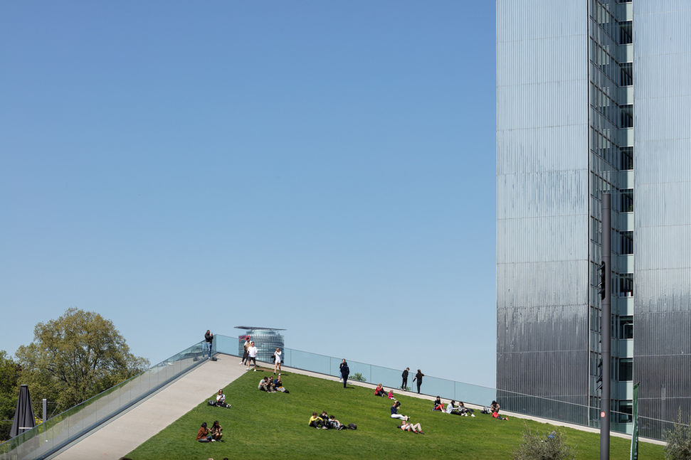 Menschen auf der grünen rasenfläche gegenüber dem Geschäftsgebäude Kö-Bogen II