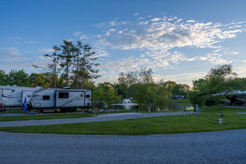 Travel trailers parked at a campground with a lake fountain.