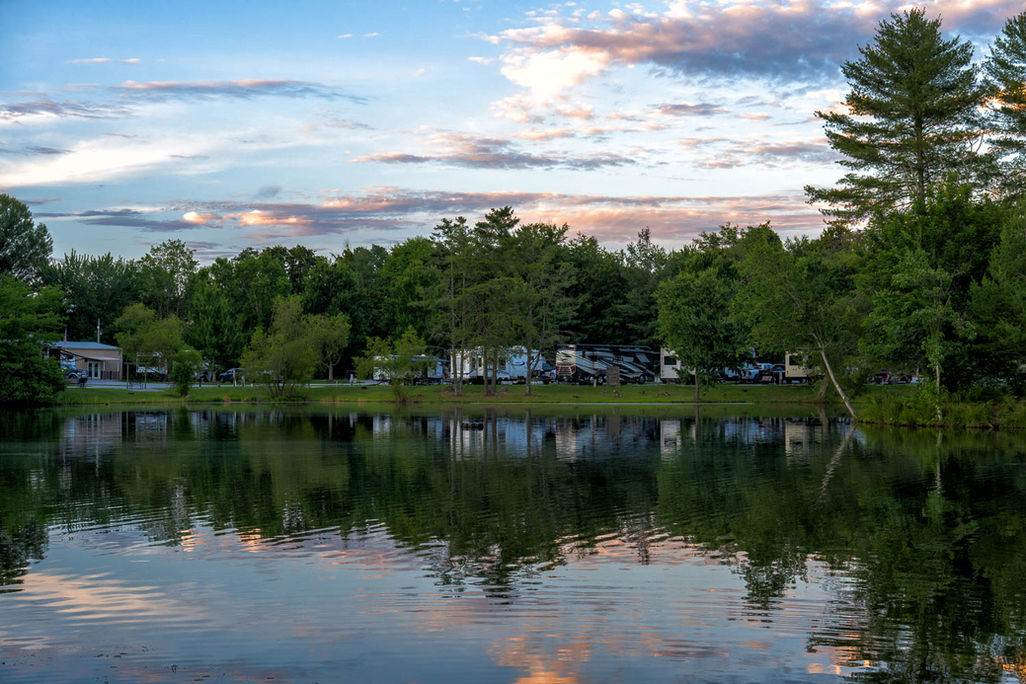 RVs parked along a peaceful lake with forest reflections.