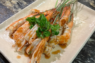 Shrimp presented with sauce and fresh herbs on a ceramic platter