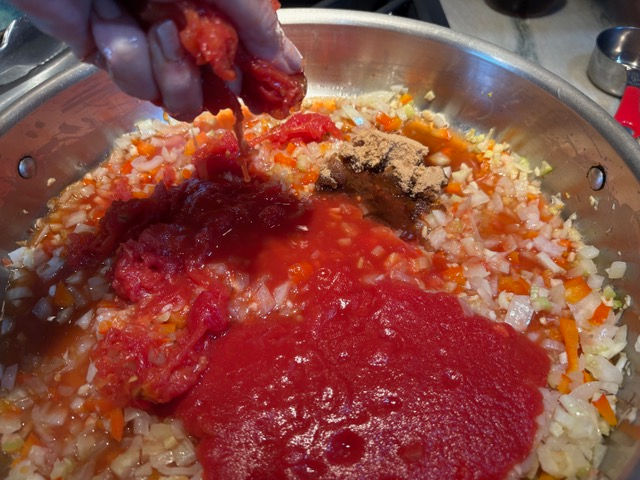 When adding the whole canned tomatoes, squeeze them in your hand to help break them up.