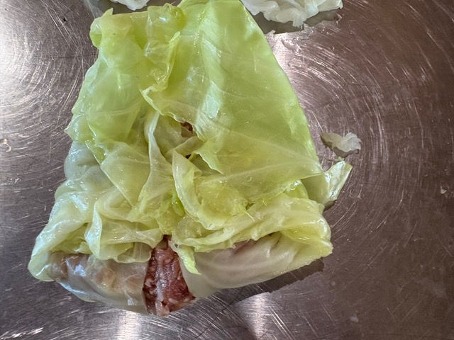 Bring the bottom of the leaf over the meat, then fold in the sides. Roll up tightly like an eggroll.