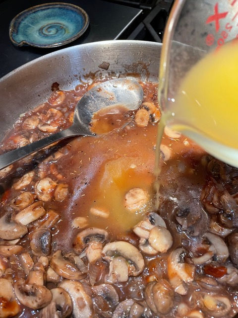 Add stock to browned mushrooms.