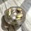 Thumbnail: Gold And Silver Wavy Plate With Painted Gold And Silver Stones, Tilted View, On Beige Marble Worktop