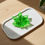 Thumbnail: Green resin maple leaf ashtray on white tray, wooden background.