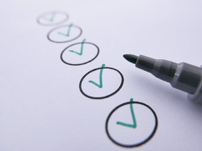 A black marker near circles with green ticks on white paper.