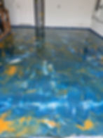 Metallic epoxy floor installation with custom vibrant ocean blue, gold, and white swirls finish in Parkland