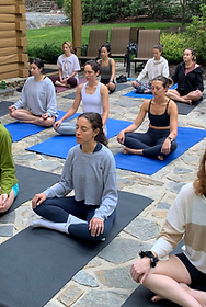 group corporate photo yoga students sitting on yoga mats in an outside setting awaiting instruction