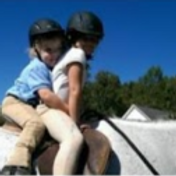 two young students riding double on grey horse