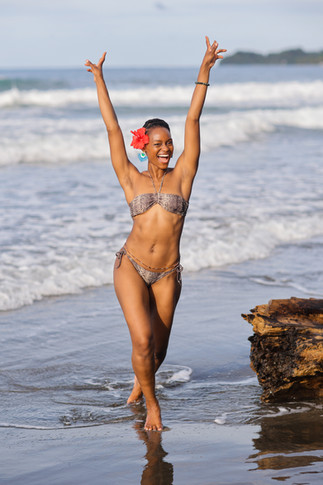 beautiful black woman excited walking on the beach with arms up posing for a photoshoot in Costa Rica