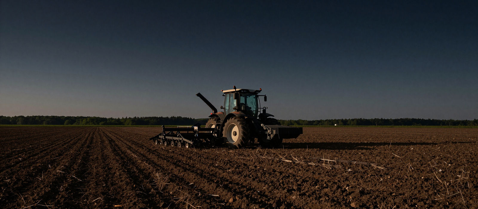A tractor working a paddock at dusk