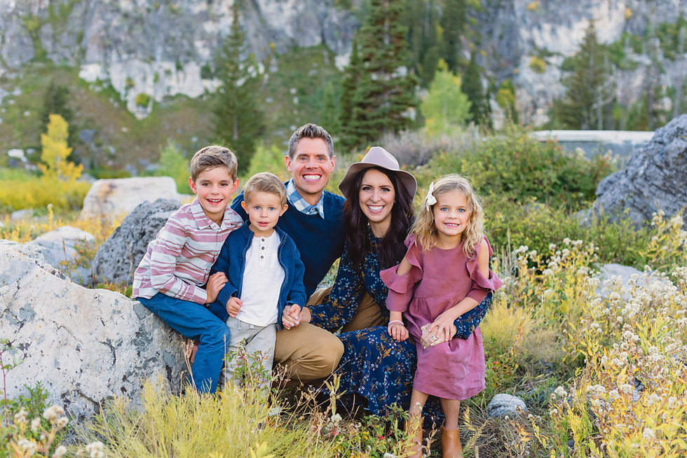 Family crouching and smiling while surrounded by fall colors at Tony Grove in Logan Canyon