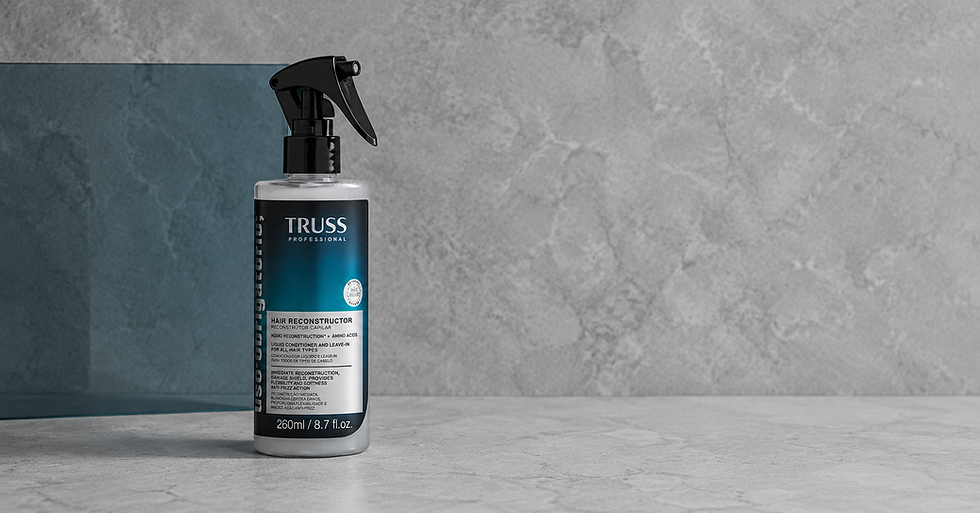 Frasco spray preto e azul da TRUSS Professional Hair Reconstructor sobre fundo cinza texturizado, com rótulo visível.