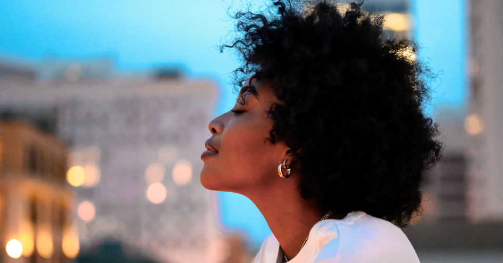 Mulher em momento de pausa consciente ao ar livre, respirando profundamente para regular emoções e reduzir a ansiedade