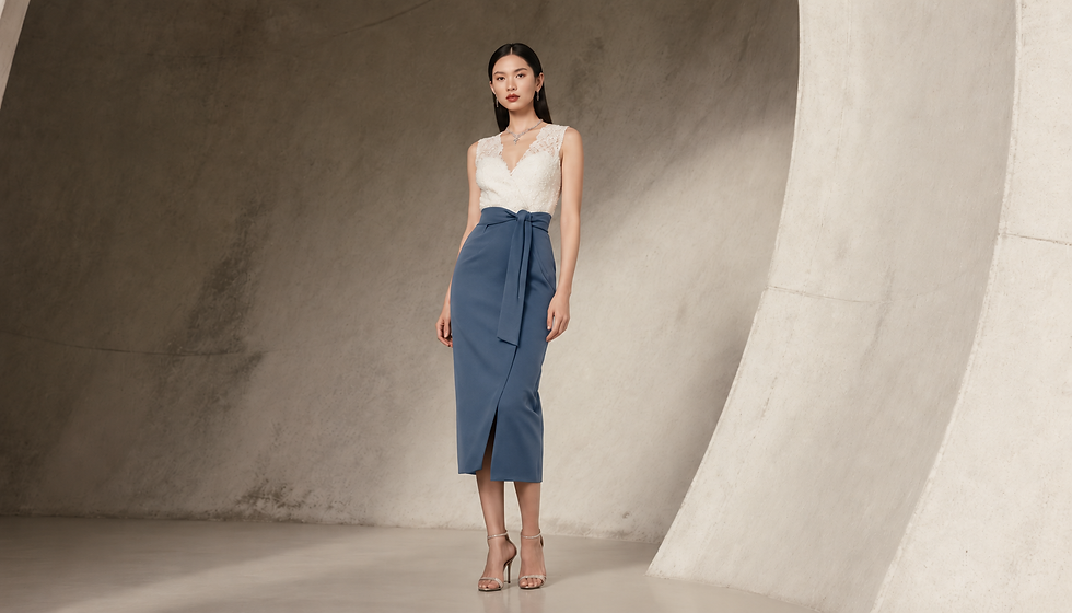 Mulher posa em estúdio minimalista, com vestido branco e saia azul, expressão serena e elegante, sobre fundo bege curvo.