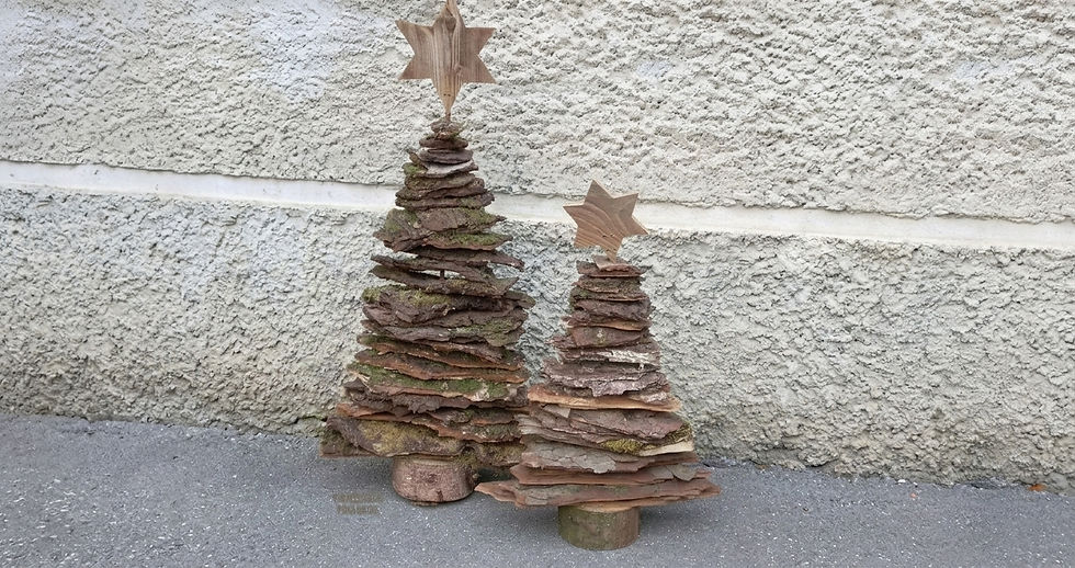Dois enfeites de pedra em forma de pinheiro com estrelas de madeira, diante de uma parede texturizada cinza.