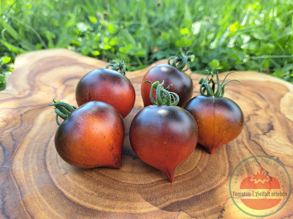 Rötlich-gelbliche Salattomate mit schwarzen Schultern und ausgepägter Spitze auf einem Holzbrett - Tomate Heaven Oregon