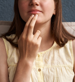 Hand of a girl practicing EFT or emotional freedom technique - tapping under the mouth.jpg