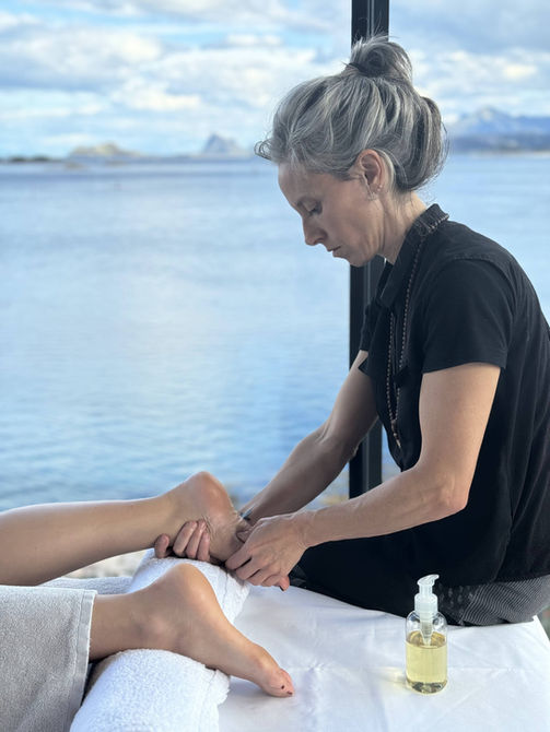Foot massage in a wooden cabin on Manshausen Island, releasing tension and softening the back of the body