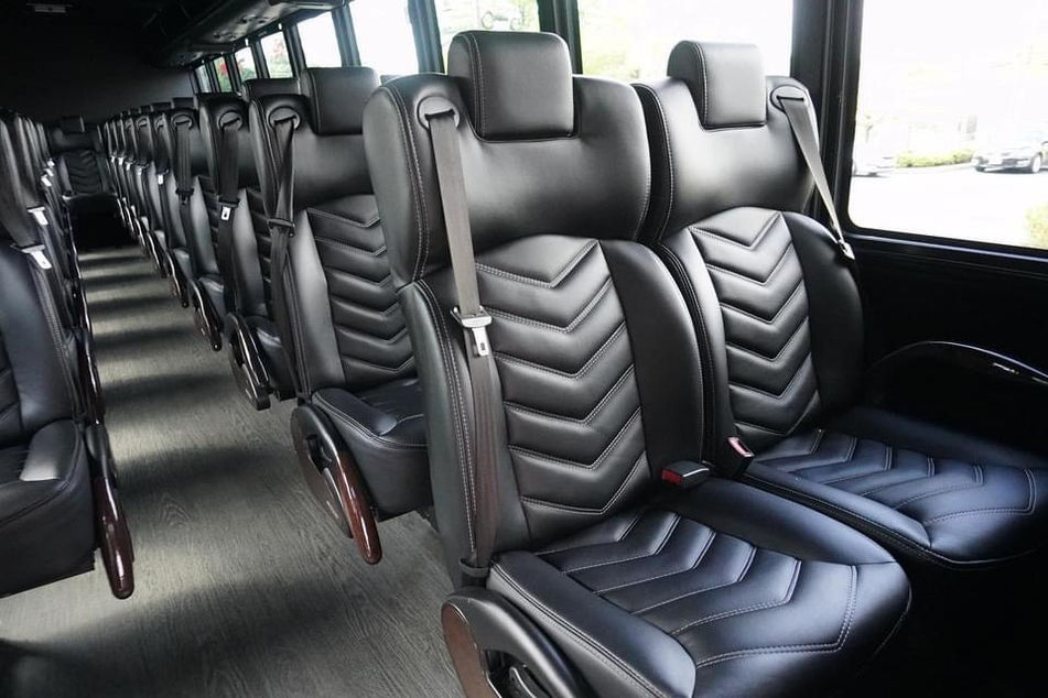 Luxurious interior of Gem Worldwide's 39-passenger Greco mini bus, showcasing plush reclining seats, ample legroom, individual climate controls, onboard bathroom, Wi-Fi, USB outlets, and spacious overhead storage, perfect for premium group travel in NJ, PA, and NY.