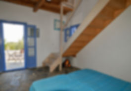 Blue bedcover and french windows opening to courtyard on a Greek island.