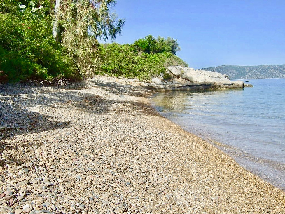 Pebbled secluded beach with rocks in the distance.
