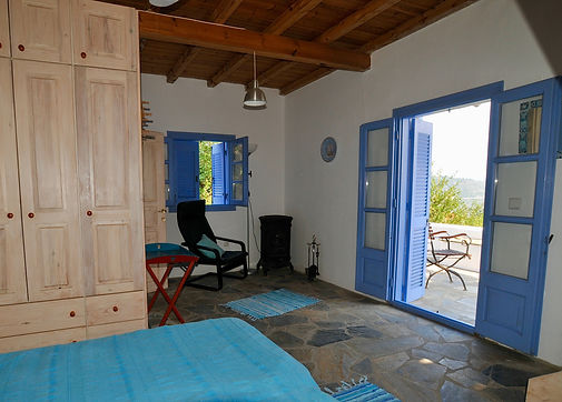 wooden wardrobe and open blue french windows to courtyard.