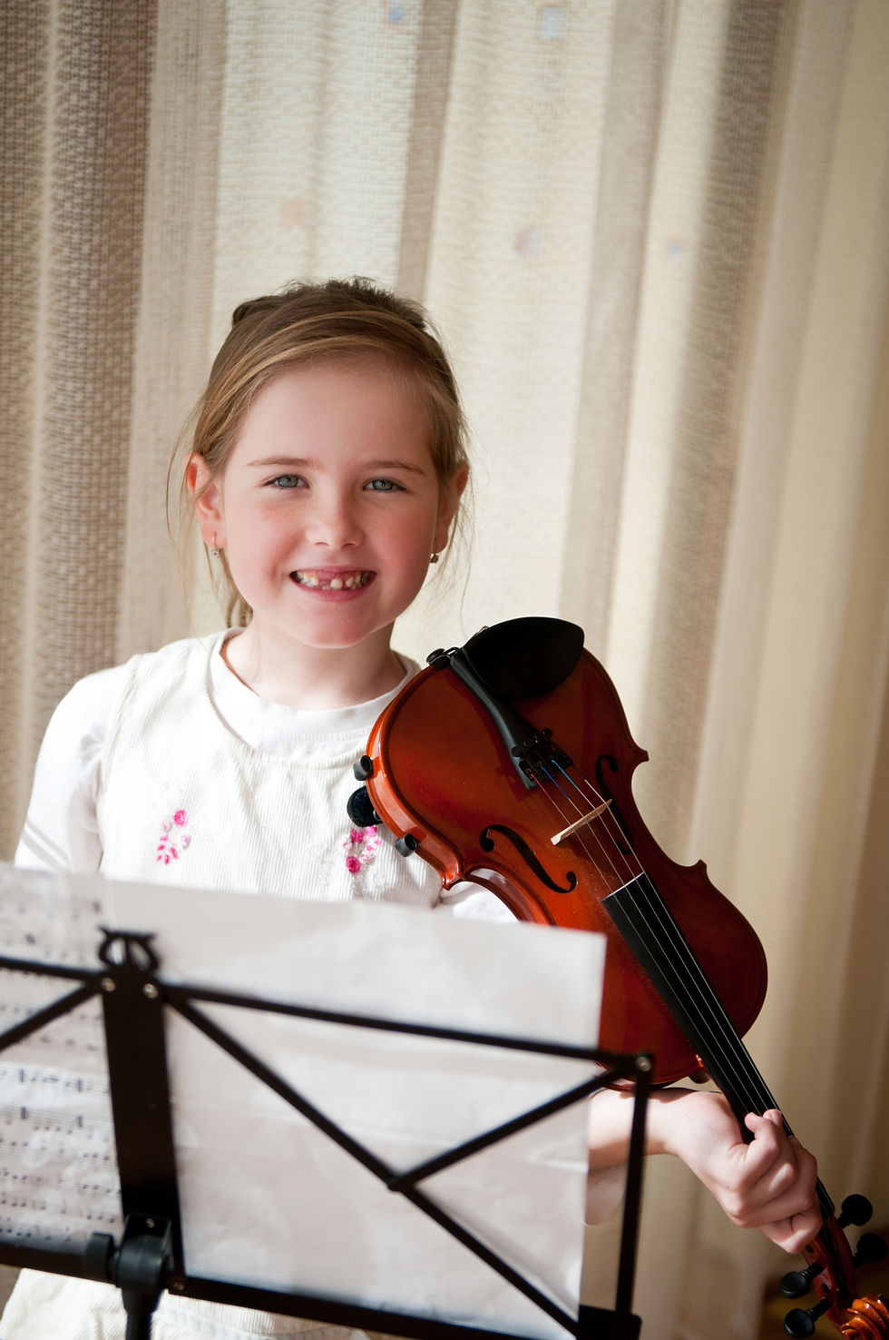 young girl smiling and playing violin