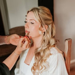 Woman having makeup applied with bridal hair & makeup during preparations for event