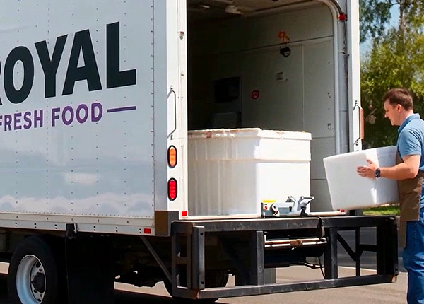 Man loading a truck with text, ROYAL FRESH FOOD. Delivering fresh products.