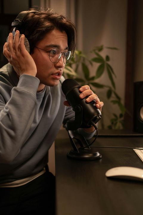 A young male Asian talking into a microphone in a Sydney studio where he is recording the voiceover for a brand video.
