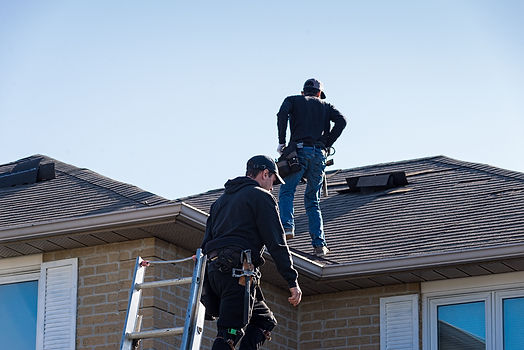 Two roofers inspecting a damaged roof.jpg