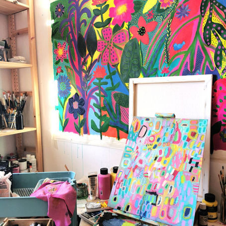 An art studio with canvas hanging on the wall and brushes and other supplies