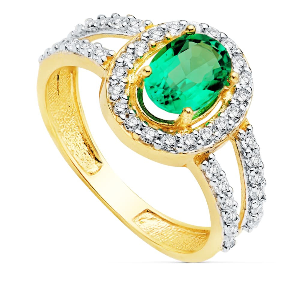 Sortija de oro bicolor 18k con esmeralda de 0.79 quilates (7x5 mm), adornada con un halo de brillantes circonitas. Elegancia