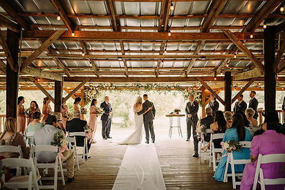 A bride and groom standing at the altar getting married surrounded by family, friends, and wedding flowers