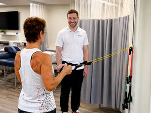 Physical therapist guiding a patient through a resistance band exercise during a rehabilitation session in Lynn, MA