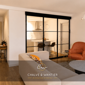 rénovation d'un appartement avec un salon à Nîmes et une verrière coulissante noire ouvrant sur la cuisine, canapé écru et fauteuil terracotta