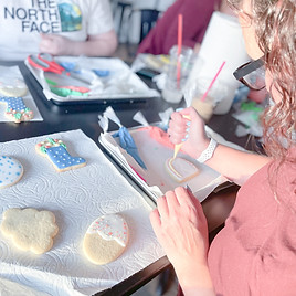 Person decorating sugar cookies with royal icing during an OH Sugar Cookie Classes workshop in Ohio.