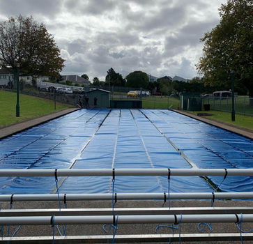 Commercial solar pool cover with heavy-duty roller frame and haul cord attachments, installed by Aquatech New Zealand