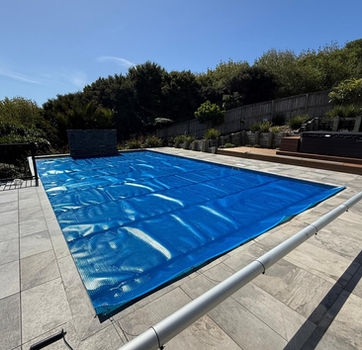 Blue solar pool blanket covering backyard pool – energy-efficient pool cover supplied by Aqua-Tech Auckland