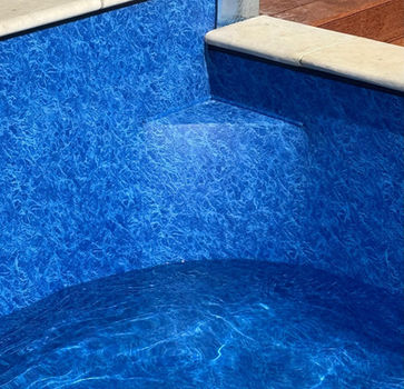 Close-up of custom-formed pool steps with blue marble vinyl liner and white coping tiles, installed by Aquatech Industries NZ