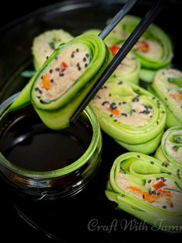 Spicy cucumber tuna rolls arranged on a plate, garnished with sesame seeds and a drizzle of spicy mayo.