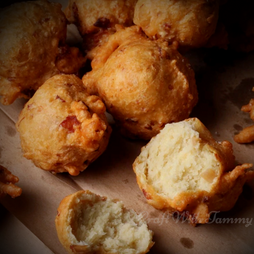 "A plate of golden-brown Rhode Island clam cakes served with lemon wedges and a side of chowder."