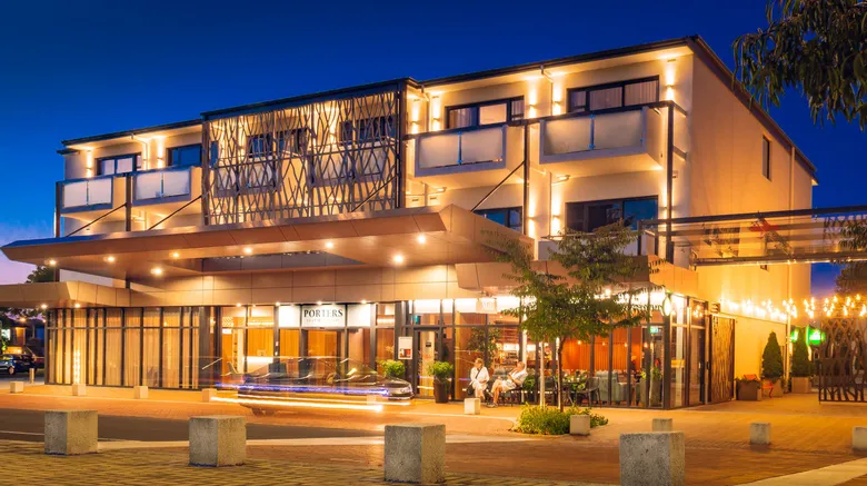 Boutique hotel in New Zealand at night, featuring a modern exterior with warm lighting, private balconies, a stylish entrance, and outdoor seating.