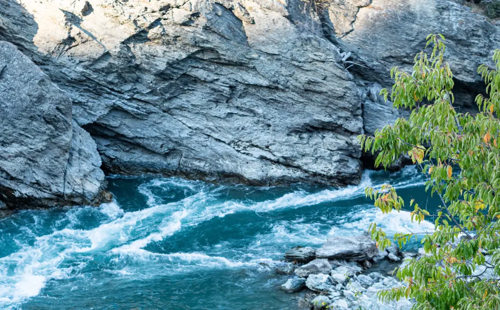 Close-up of the Kawarau Gorge in New Zealand, with turquoise water rushing through rugged rock formations.