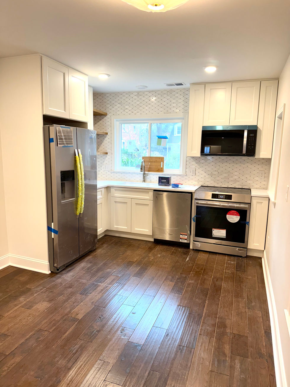 Contemporary kitchen with dark wood floors, white cabinetry, and stainless steel appliances.